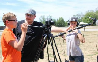 Film camp students around a camera